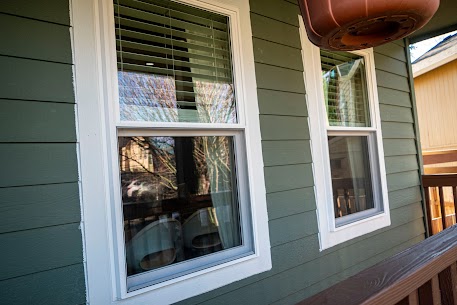 Completed window replacement in green lap siding, double-hung windows with white trim installed by Left Coast Exteriors